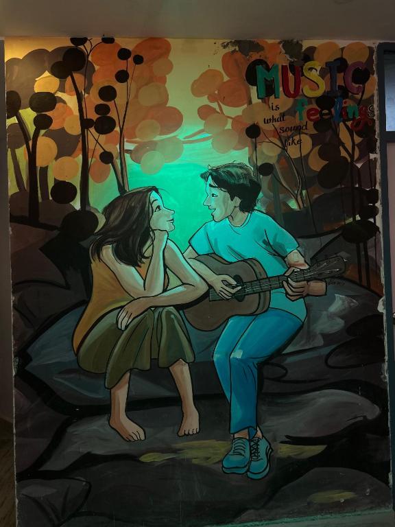 a painting of a man and a woman playing a guitar at ZoukStayz in Rishīkesh