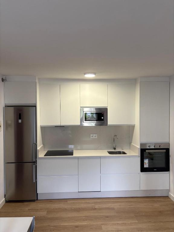 a kitchen with white cabinets and a stainless steel refrigerator at Apartamento Louro in Louro