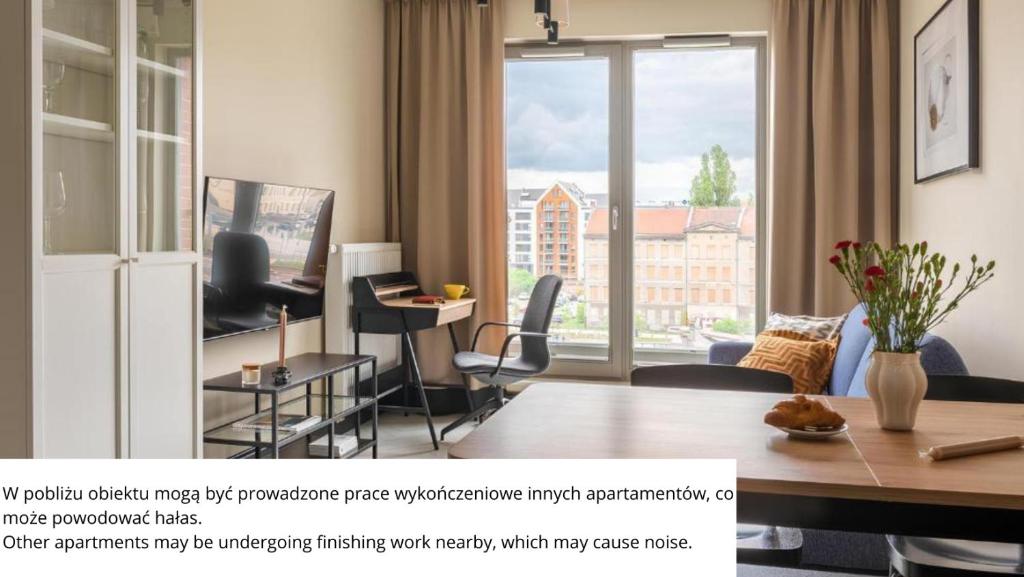 un soggiorno con un tavolo e una grande finestra di Flatbook - City Center SPA Apartments Grano Residence with Parking a Danzica
