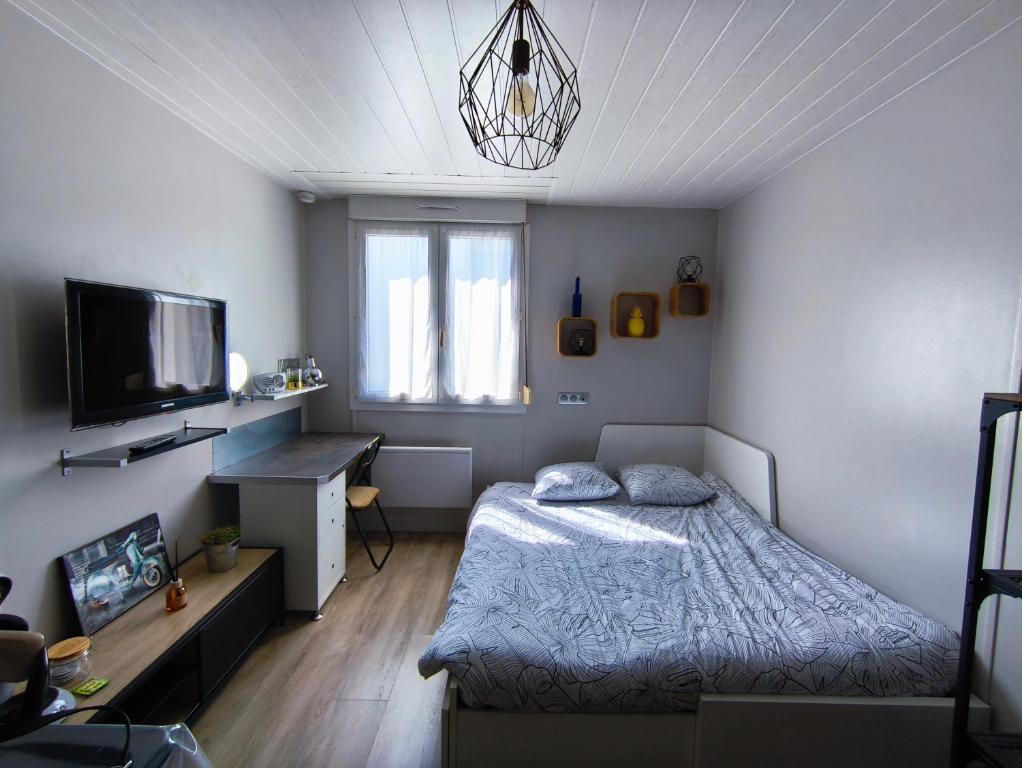 une chambre avec un lit, un bureau et une télévision dans l'établissement Le Cardinal, à La Rochelle