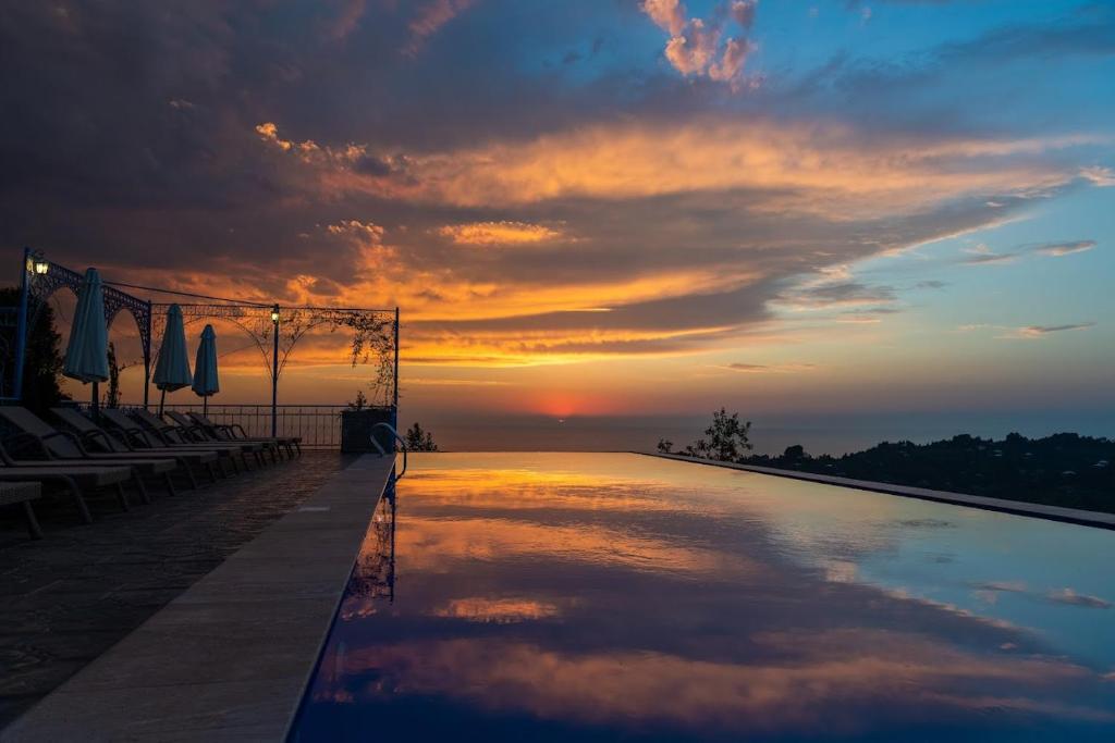 a swimming pool with a sunset in the background at Roots Resort in Kobuleti