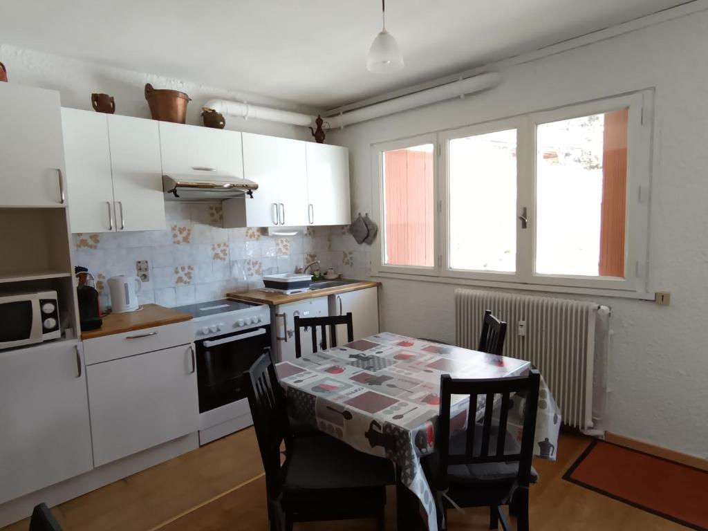 une cuisine avec une table et des chaises et une table et une fenêtre dans l'établissement Appartement 2 chambres, 4 pers, terrasse, animaux acceptés, proche pistes et commerces - Montgenèvre - FR-1-445-80, à Montgenèvre