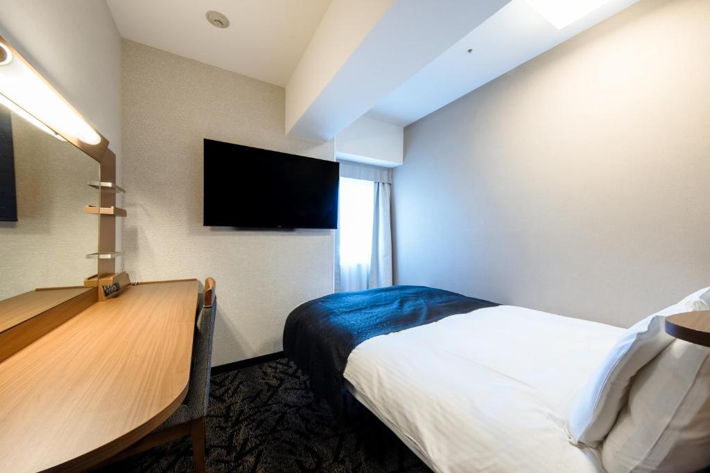 a hotel room with a bed and a flat screen tv at APA Hotel Tennoji Ekimae in Osaka