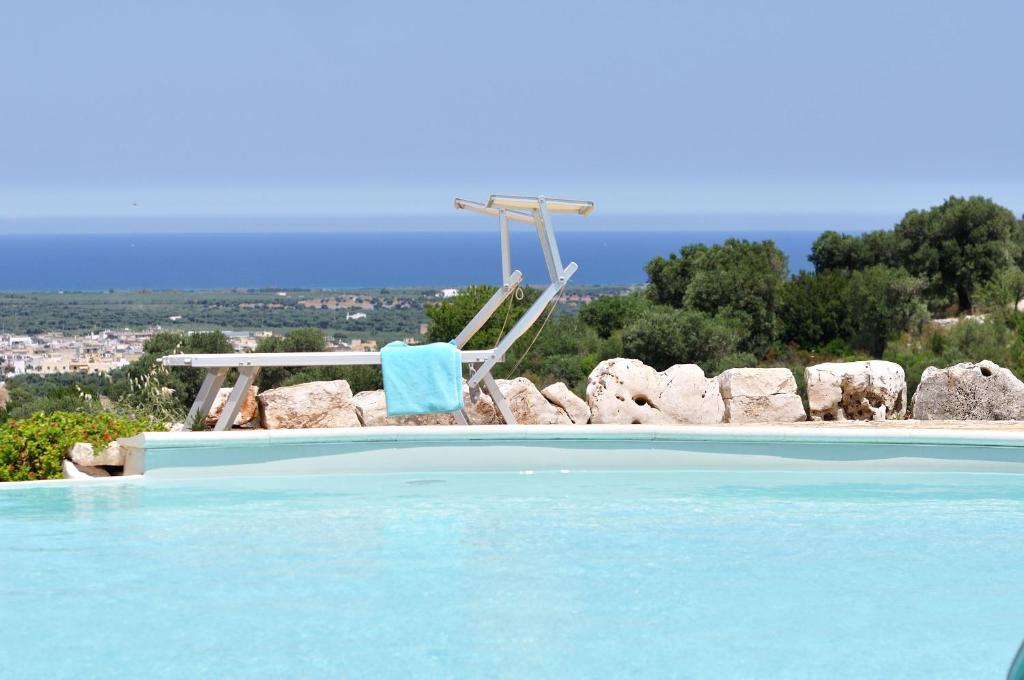 a swimming pool with a chair and a swing at AGRITURISMO Masseria Spetterrata in Cisternino