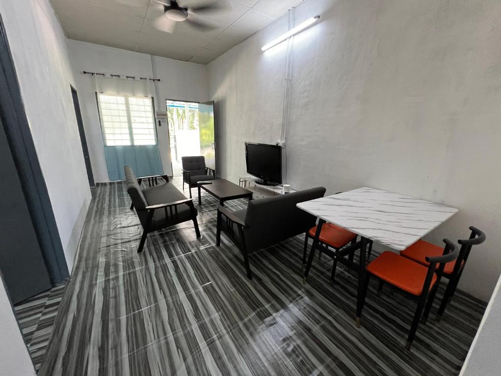 a living room with a table and chairs and a television at CK Homestay Parit Buntar Perak in Bagan Serai