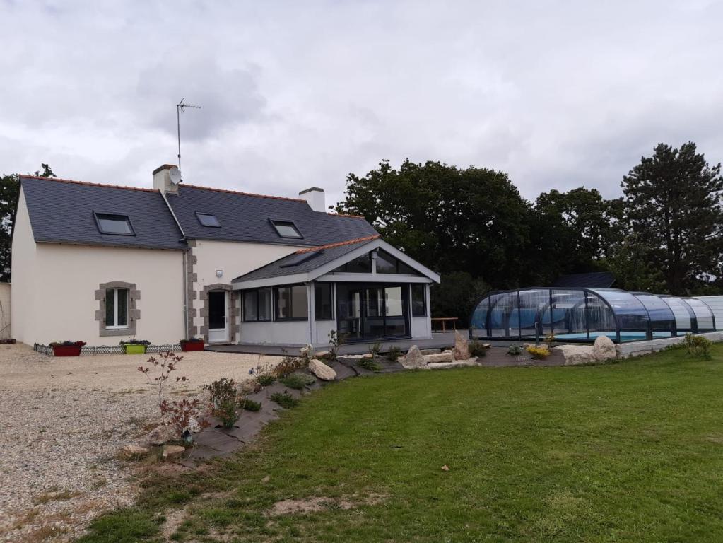 une maison blanche avec une serre dans une cour dans l'établissement Maison prés des plages, à Névez