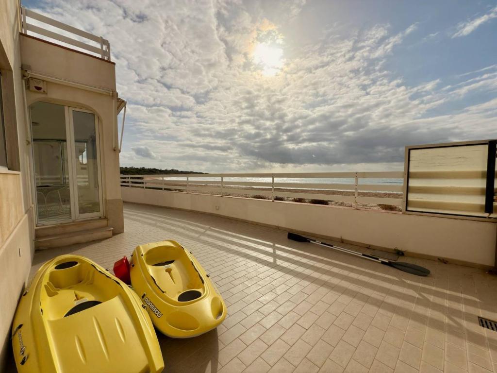 two yellow kayaks sitting on the balcony of a building at iDream on the sea in Punta Braccetto