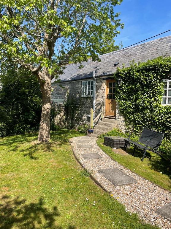 a house with a tree and a bench in front of it at Gardeners Cottage in Mudford