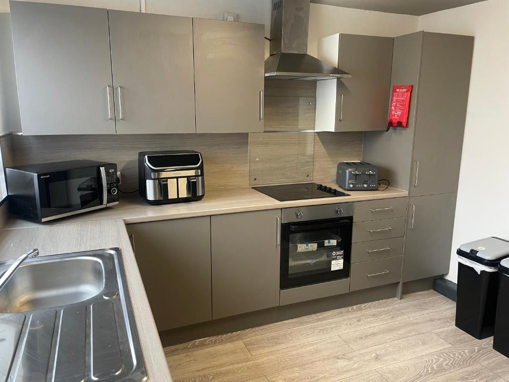 a kitchen with a sink and a microwave at 1 Bed Flat with King or Twin Beds, Sofa Bed, Work space, Dining and SMART TV with Free Wifi Throughout! in Wingate