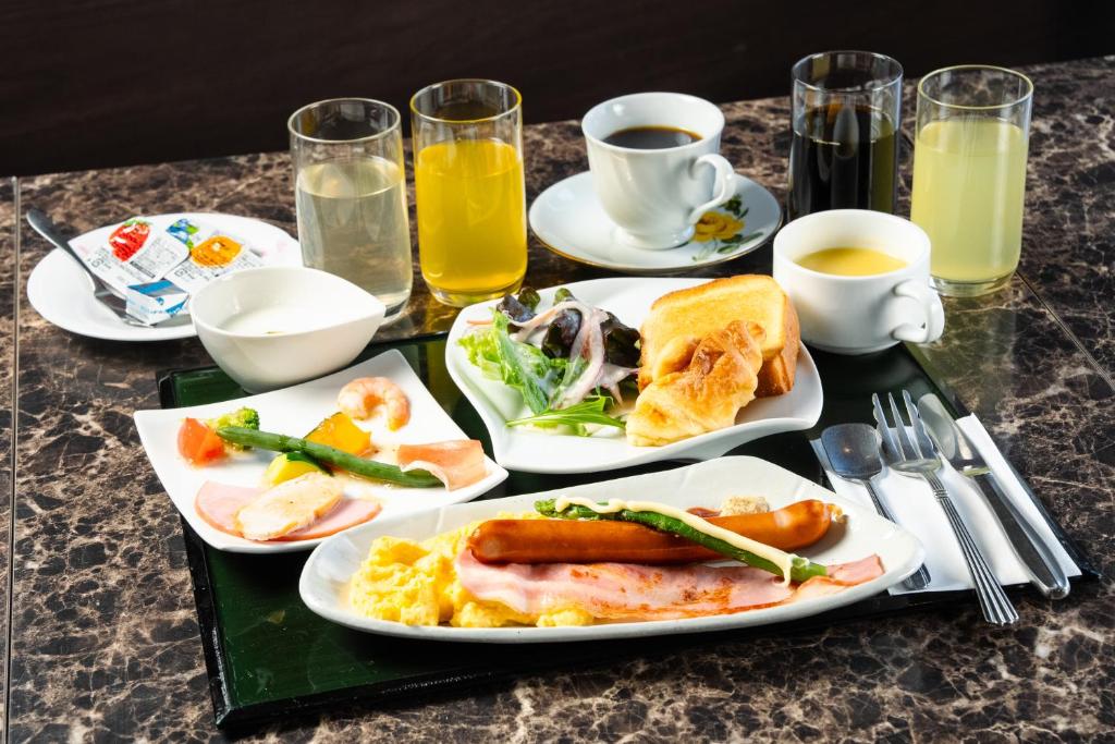 a table with plates of food and cups of orange juice at APA Hotel Tennoji Ekimae in Osaka
