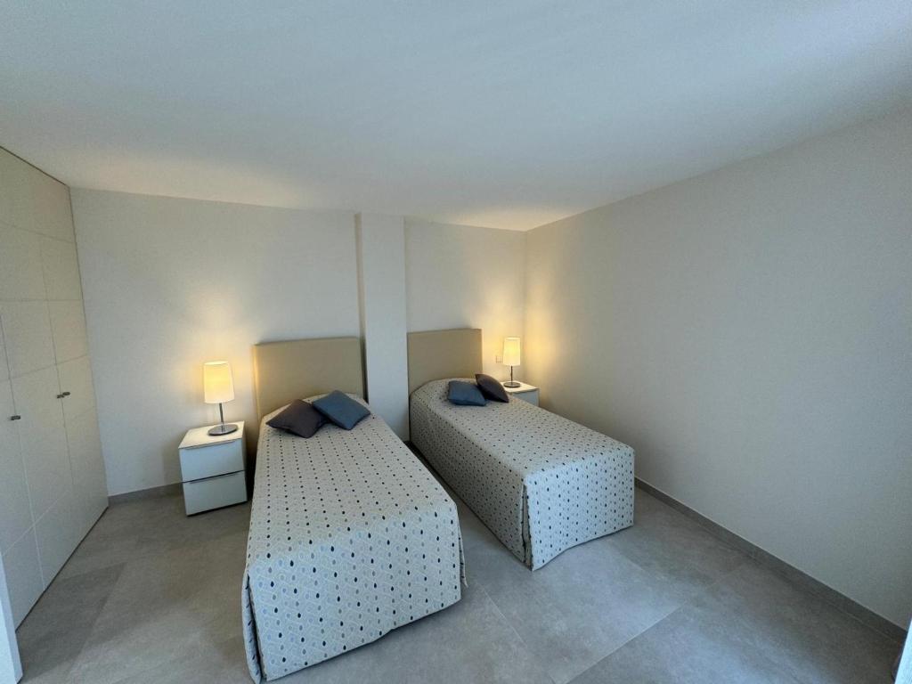 2 camas en una habitación pequeña con 2 lámparas en GRAND HOTEL Résidence, en Cannes