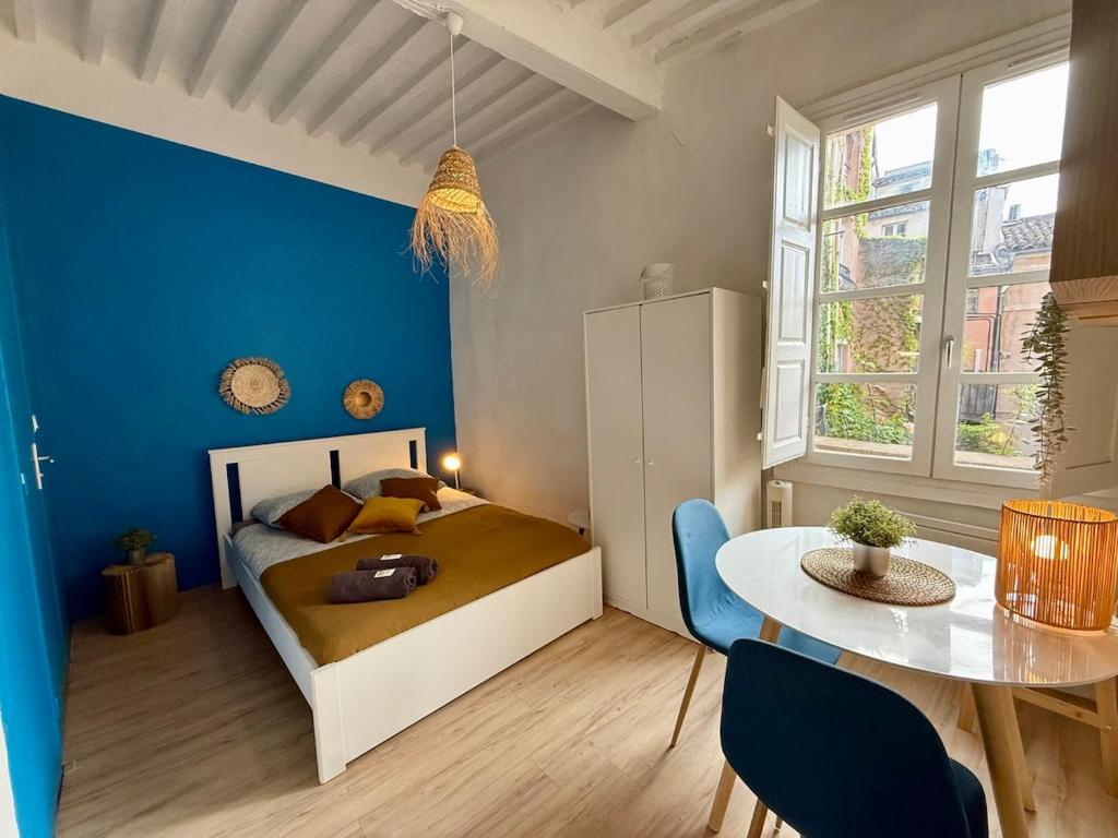 - une chambre avec un lit, une table et un mur bleu dans l'établissement Studio centre Aix-en-Provence, à Aix-en-Provence