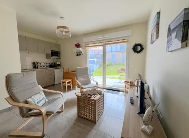 Il comprend un salon avec deux chaises et une cuisine. dans l'établissement Appartement Remember à 700m de l'Océan, à Mimizan-Plage