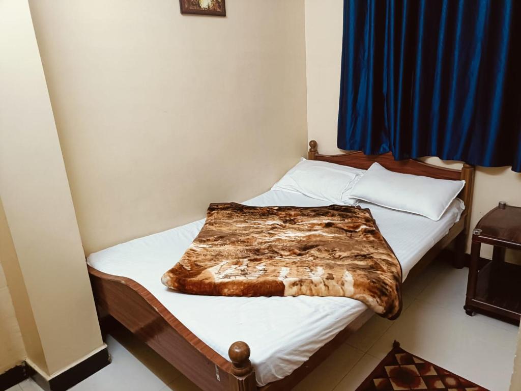 a bedroom with a bed with a blanket on it at Yamuna Residency by HRS Stays in Ooty