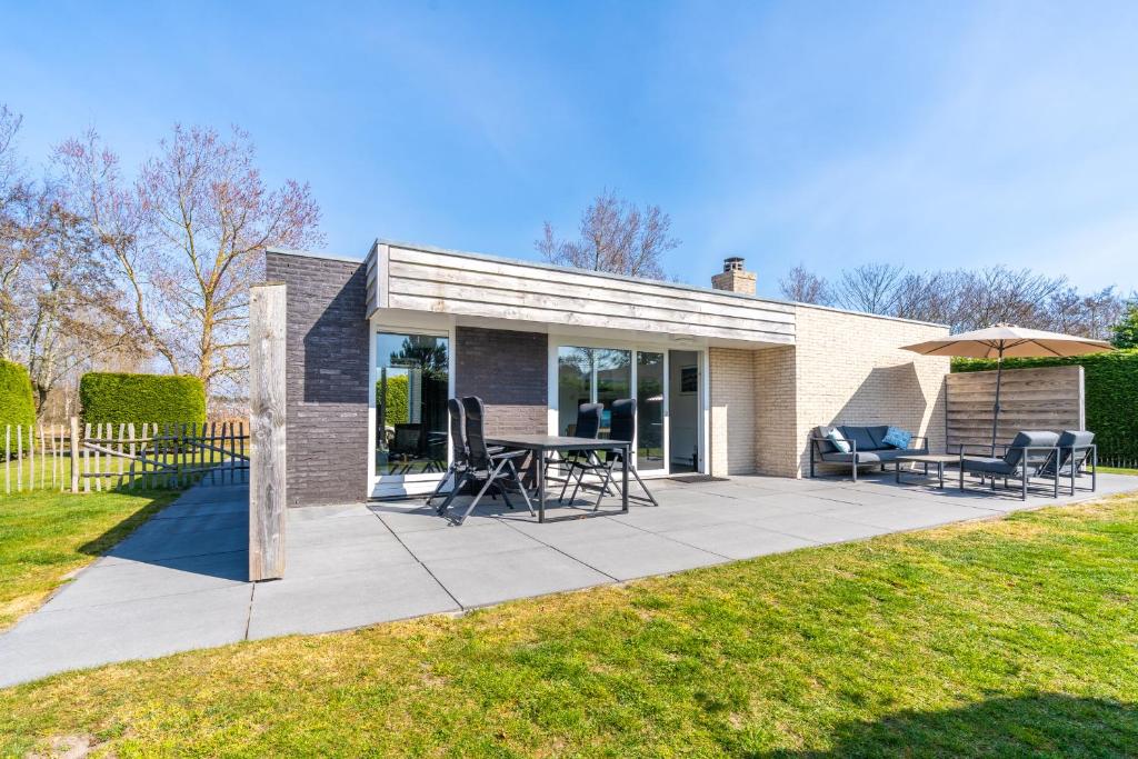 a patio with a table and chairs and an umbrella at Hoogelandt 90A in De Koog
