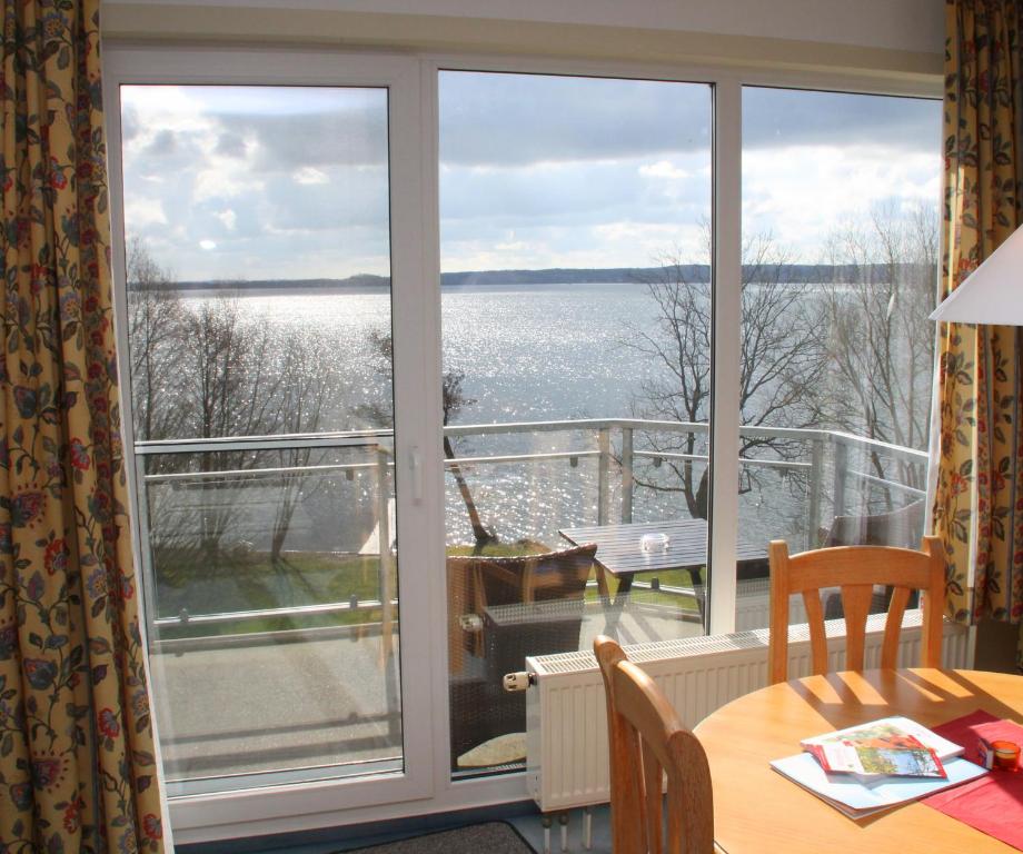 a balcony with a table and a view of the water at Apartment am Großen Plöner See in Ascheberg
