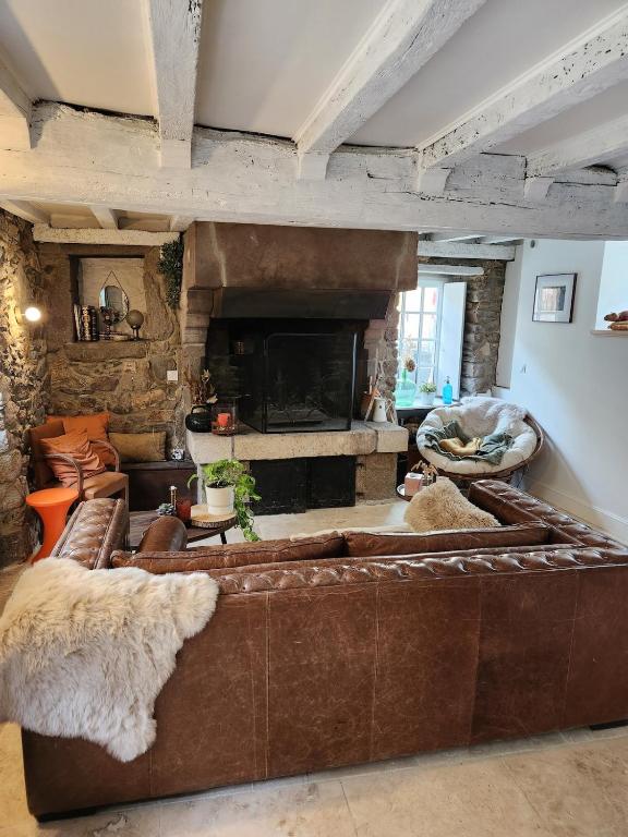 - un salon avec un canapé brun et une cheminée dans l'établissement Charmante, maison de village, plage à proximité, à Saint-Suliac