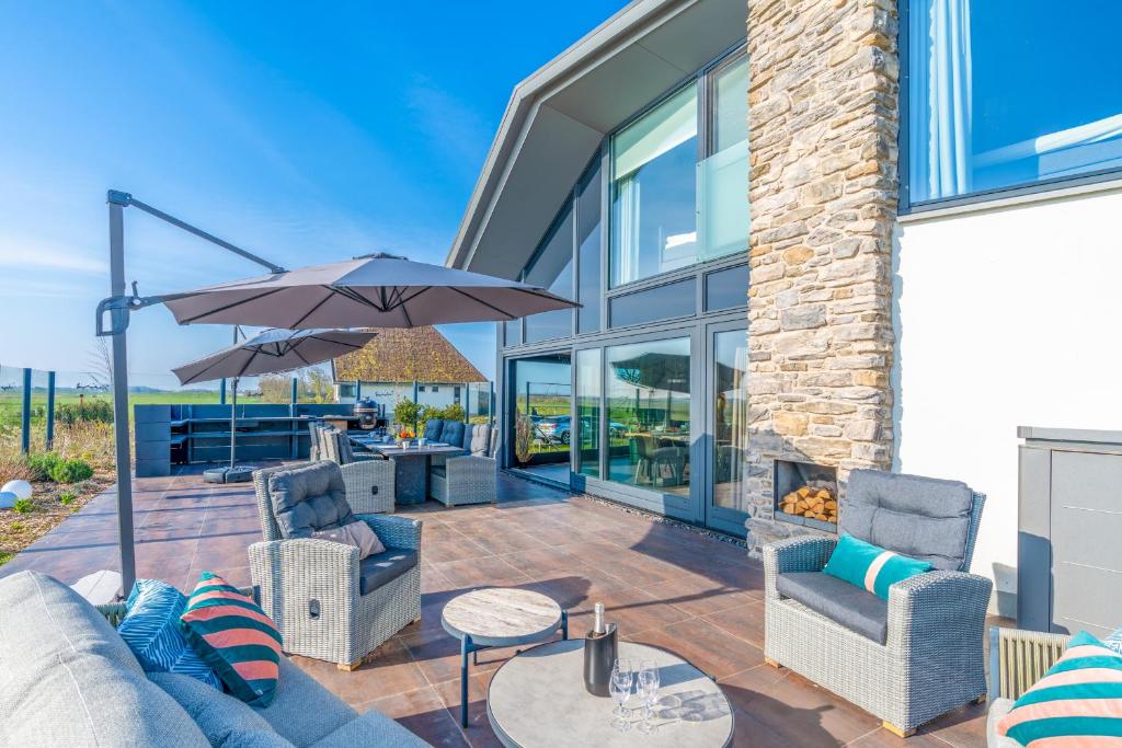 a patio with a couch and chairs and an umbrella at Natuurvilla 18 Waswaal in De Waal
