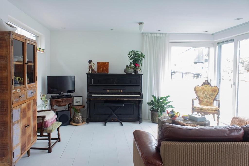 a living room with a couch and a piano at Lovely cozy houseboat Rembrandt, old centre Leiden in Leiden