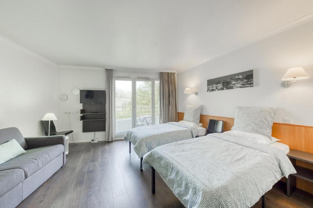 une chambre d'hôtel avec deux lits et un canapé dans l'établissement 7mn walk to Metro, in ApartHotel, à Courbevoie