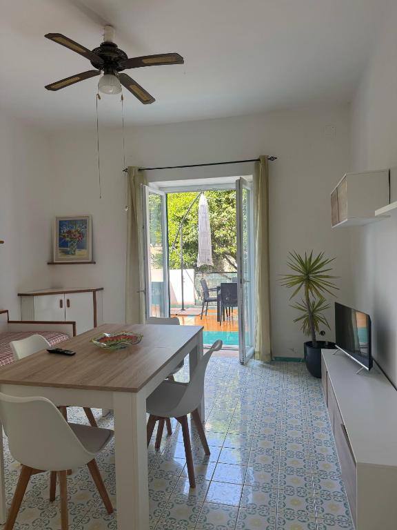 a living room with a dining room table and a ceiling fan at Appartamento in villa in Forio d'Ischia