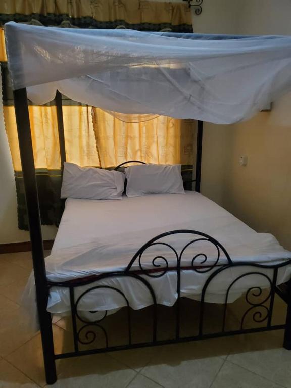 a bed with a canopy with white sheets and pillows at 2M lodge Tarangire in Manyara