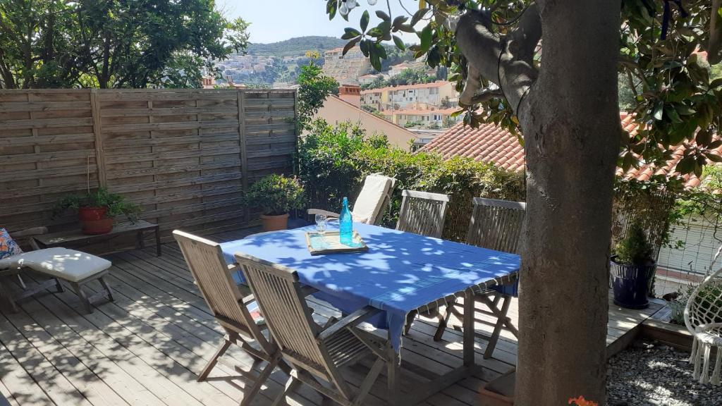 une table bleue et des chaises sur une terrasse avec un arbre dans l'établissement LA CIGALE STUDIO à port vendres, à Port-Vendres