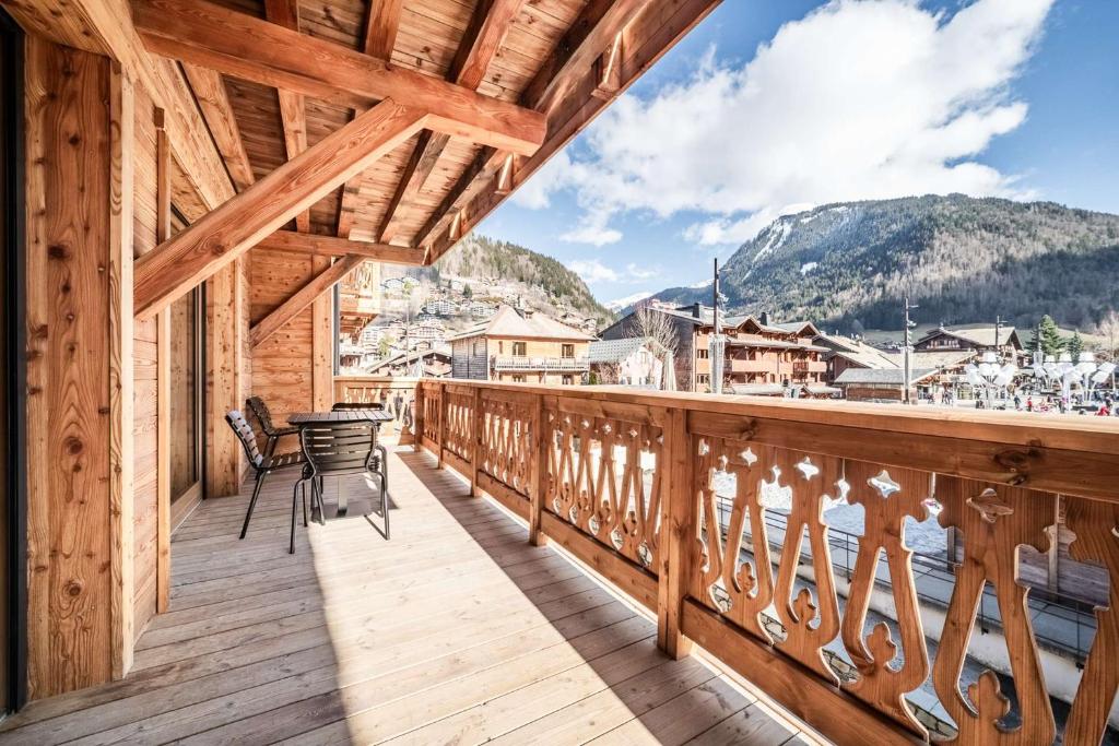 - un balcon en bois avec une table et des chaises dans l'établissement La Terrasse de Nyon Magnifique T4 cabine au centre du village, à Morzine