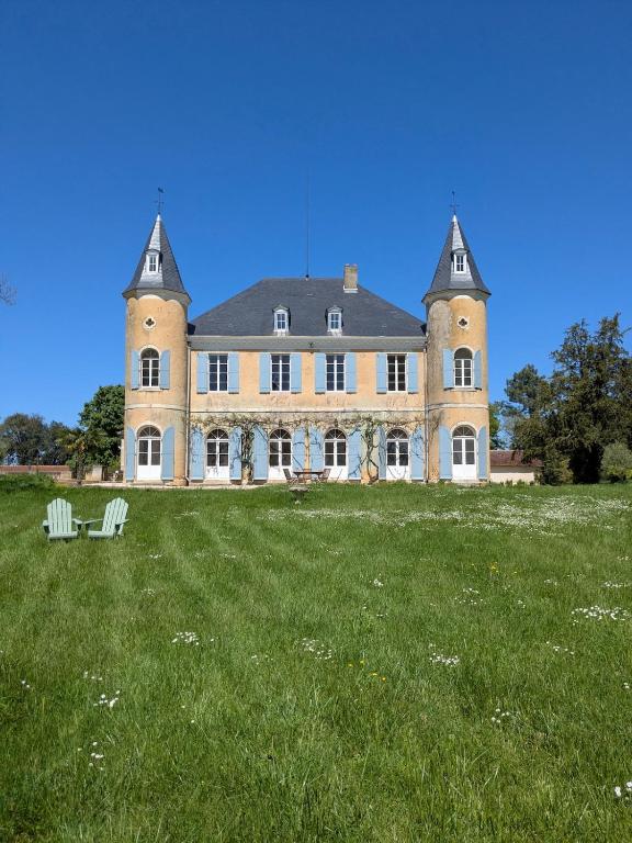 une grande maison avec deux chaises dans un champ dans l'établissement Chateau de Pomiro chambres d'hôtes et gîte, à Montréal