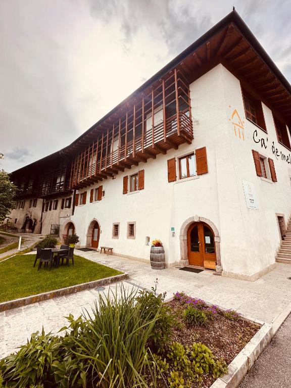 a large white building with a wooden roof at Agritur Ca' de Mel in Fiavè