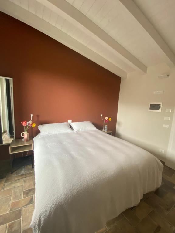 1 dormitorio con 1 cama blanca grande y pared marrón en Fuoridicampo blu, en Roncovetro