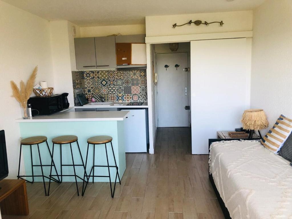 - un salon avec un lit et une cuisine avec des tabourets dans l'établissement Studio Carnon proche plage et port, à Mauguio