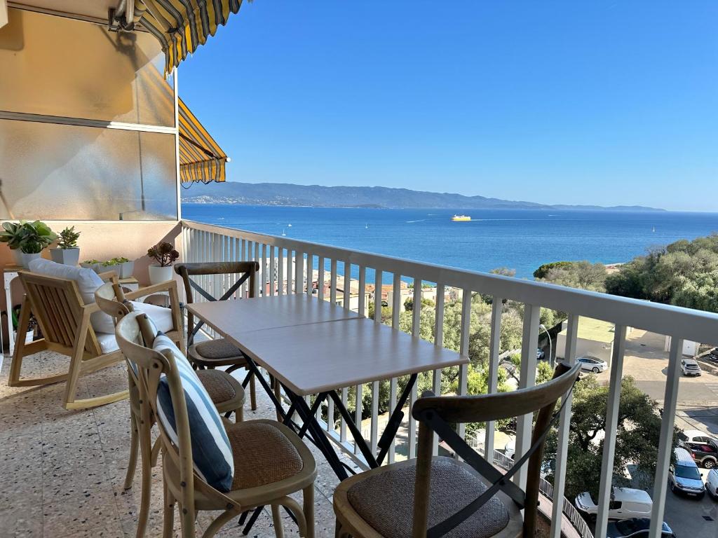 une table et des chaises sur un balcon avec vue sur l'océan dans l'établissement Magnifique appartement 3 pièces avec double vue mer, à Ajaccio