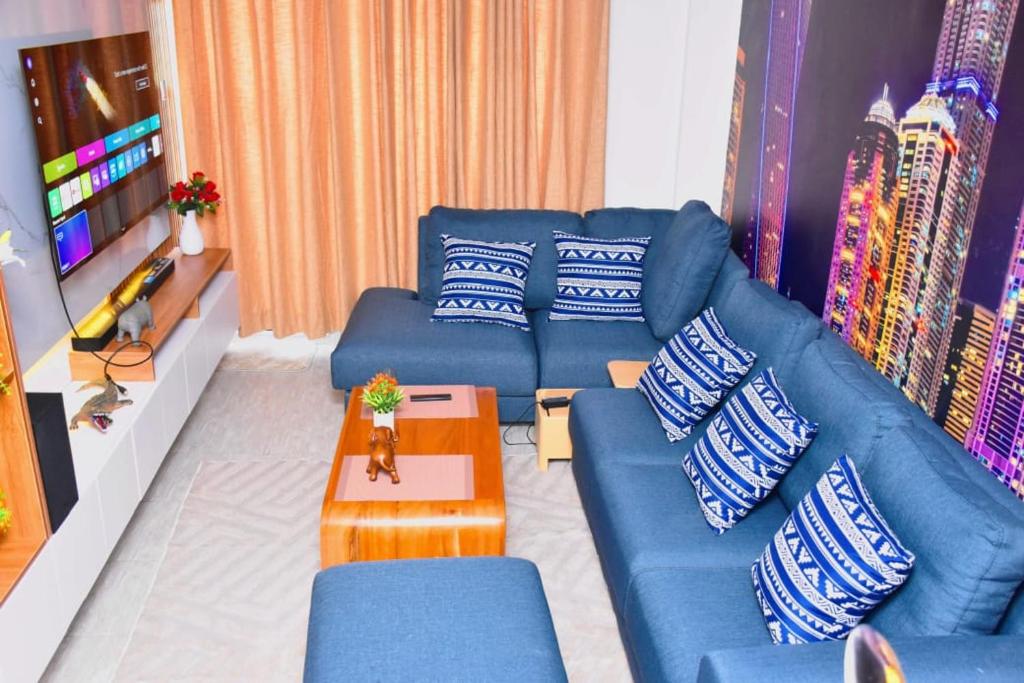 un salon avec des canapés bleus et une télévision dans l'établissement IMELA APARTMENT opposite ku referral, à Gatunga