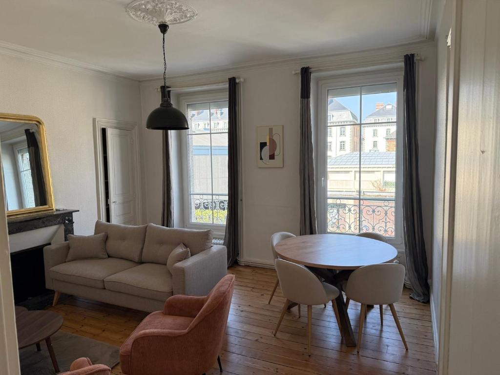 a living room with a couch and a table and chairs at L'authentique - Hyper centre et Gare in Saint-Brieuc