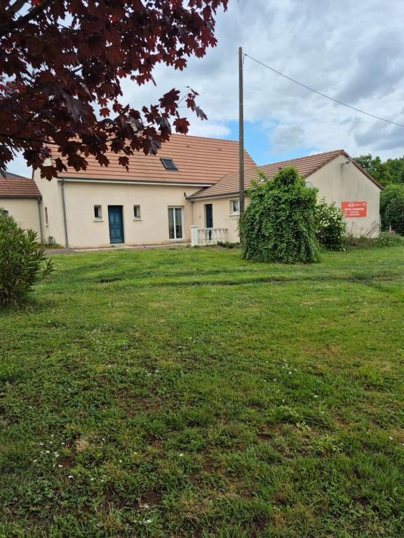 une maison avec une cour d'herbe devant elle dans l'établissement Pôle Européen du Cheval - Gîte de la Fromenterie, à Yvré-lʼÉvêque