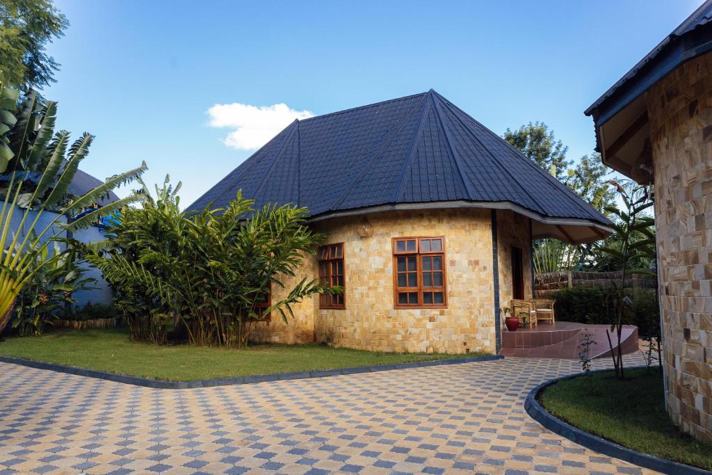 a small house with a black roof on a brick driveway at Shoki Shoki Lodge Arusha in Arusha