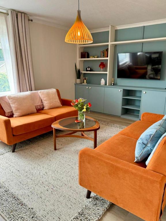 a living room with two orange couches and a tv at Vintage Vibes in Weston-super-Mare
