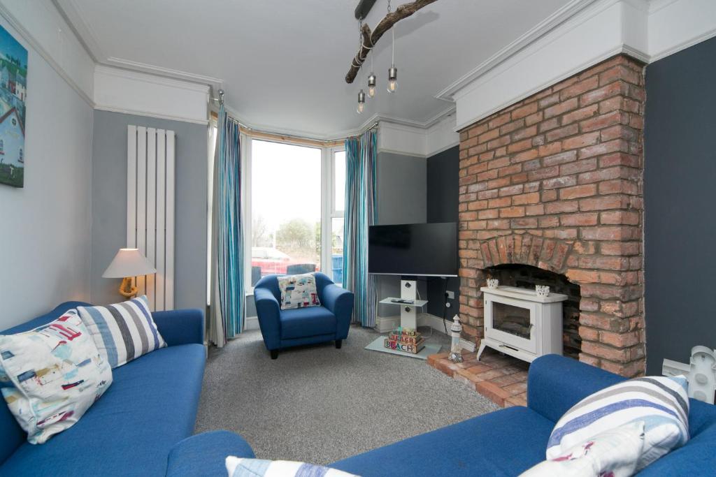 a living room with a blue couch and a fireplace at 6 Afallon, Beachside holiday house in Criccieth