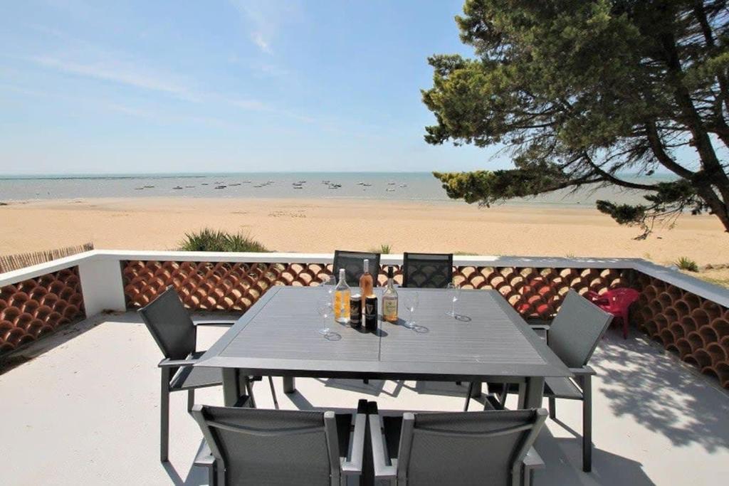 - une table et des chaises sur une terrasse donnant sur la plage dans l'établissement RARE Villa bord de mer, à La Tranche-sur-Mer