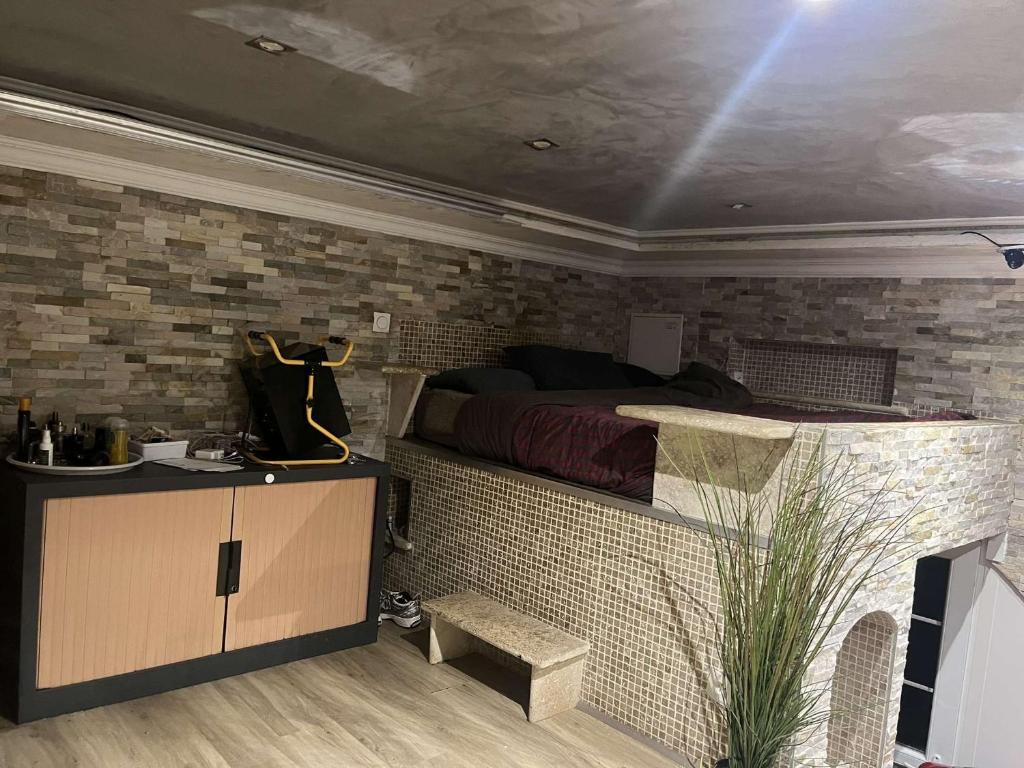 une chambre avec un lit et un mur de briques dans l'établissement Le foyer des gourmands, à Saint-Fons