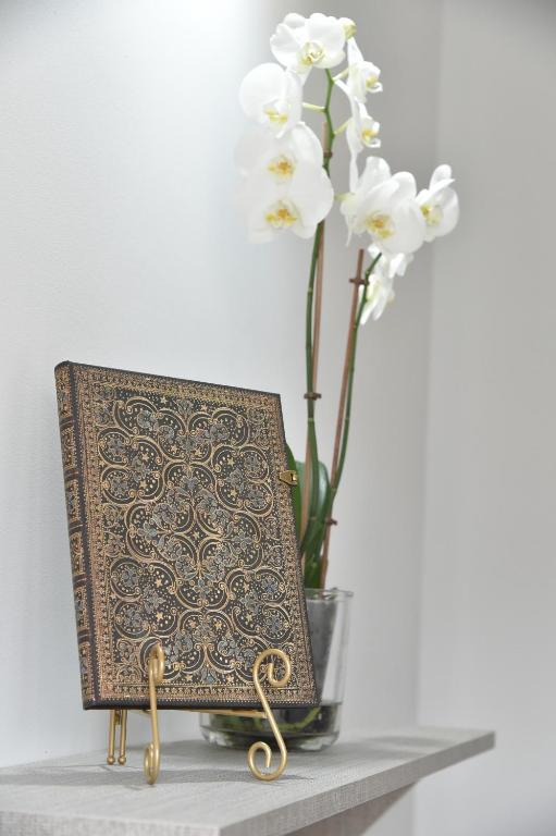 a book on a table next to a vase with flowers at BLISS HOUSE Primariei in Oradea