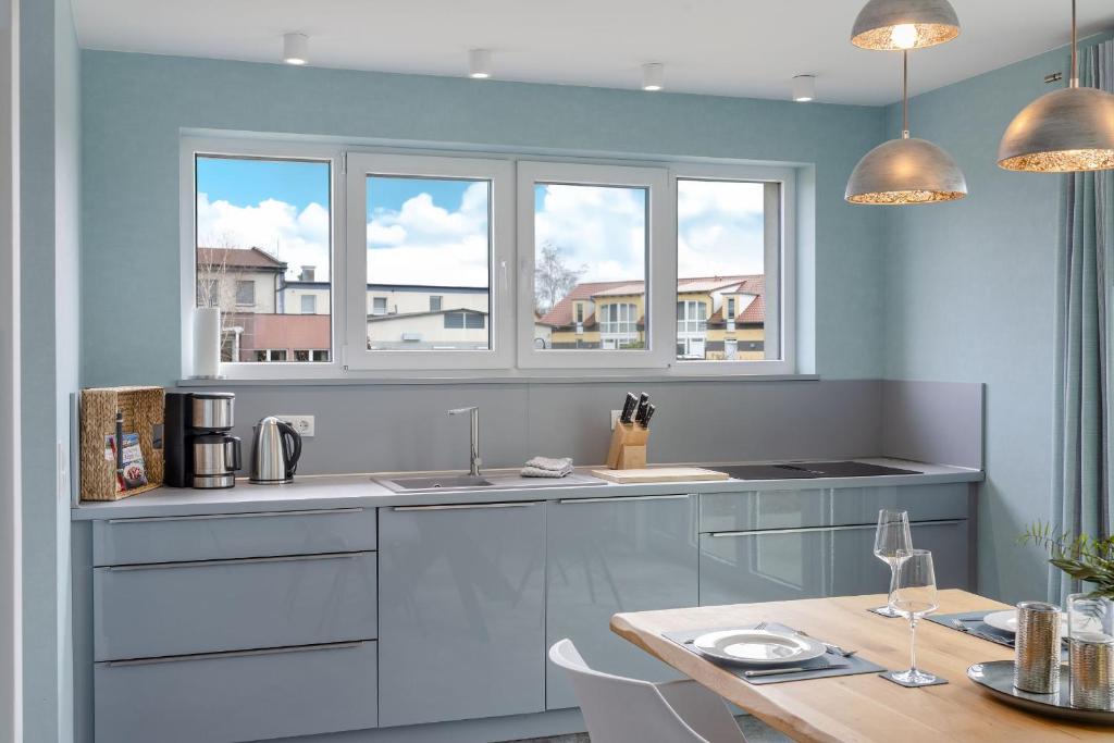 a kitchen with two windows and a table and a counter at Ferienhaus Neukamp 17E Robbenhütte in Putbus