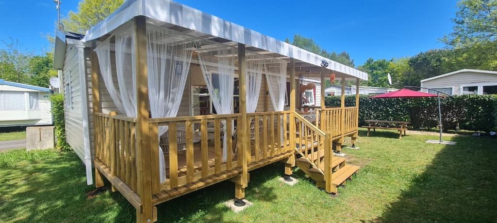 een houten prieel met gordijnen op het gras bij "Havre de paix Gastes MH 109" in Gastes