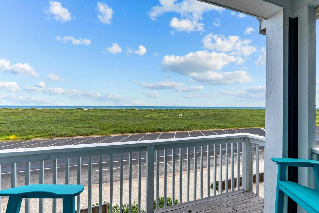 a balcony with two chairs and a view of the ocean at Tiki House in Corpus Christi