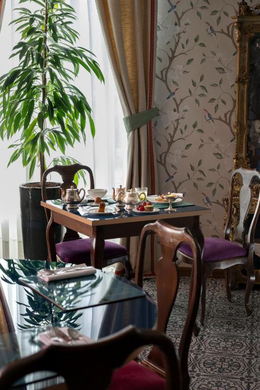 a dining room with a table and chairs and a plant at Palace Hotel in Viareggio