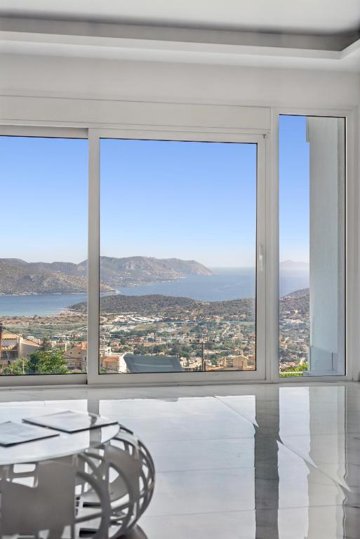 a dining room with a table and large windows at Sea View Residence Panorama Villa in Saronida