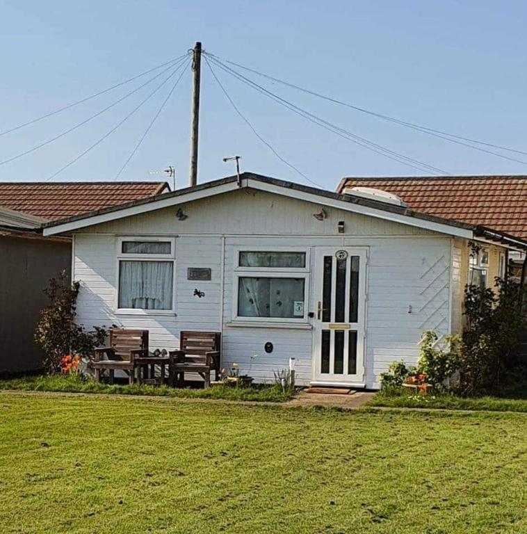 a white house with a bench in front of it at Animal friendly Sea 2 mins away in Trusthorpe
