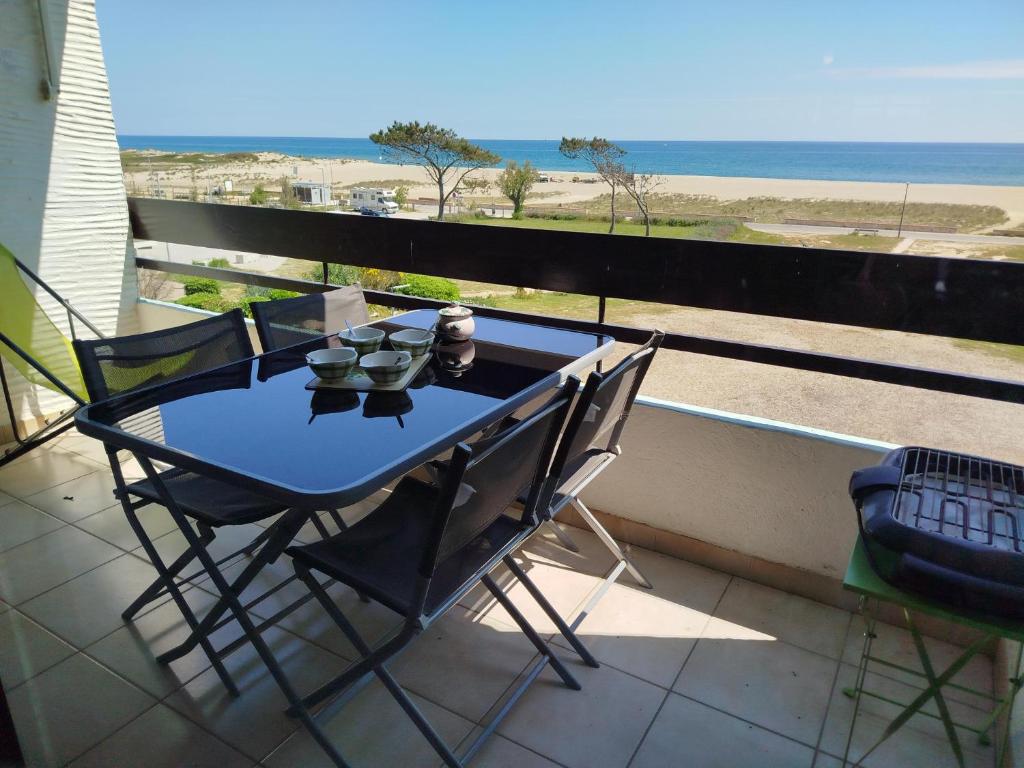 einen Tisch und Stühle auf einem Balkon mit Blick auf den Strand in der Unterkunft Appartement T2 Front de mer avec parking privatif - 4PC216 in Saint Cyprien Plage