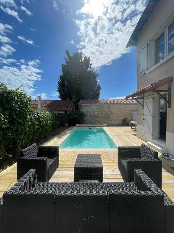 - une piscine avec 2 chaises et une table à côté d'une maison dans l'établissement Maison avec Piscine Chauffée, 6 pers, à Royan